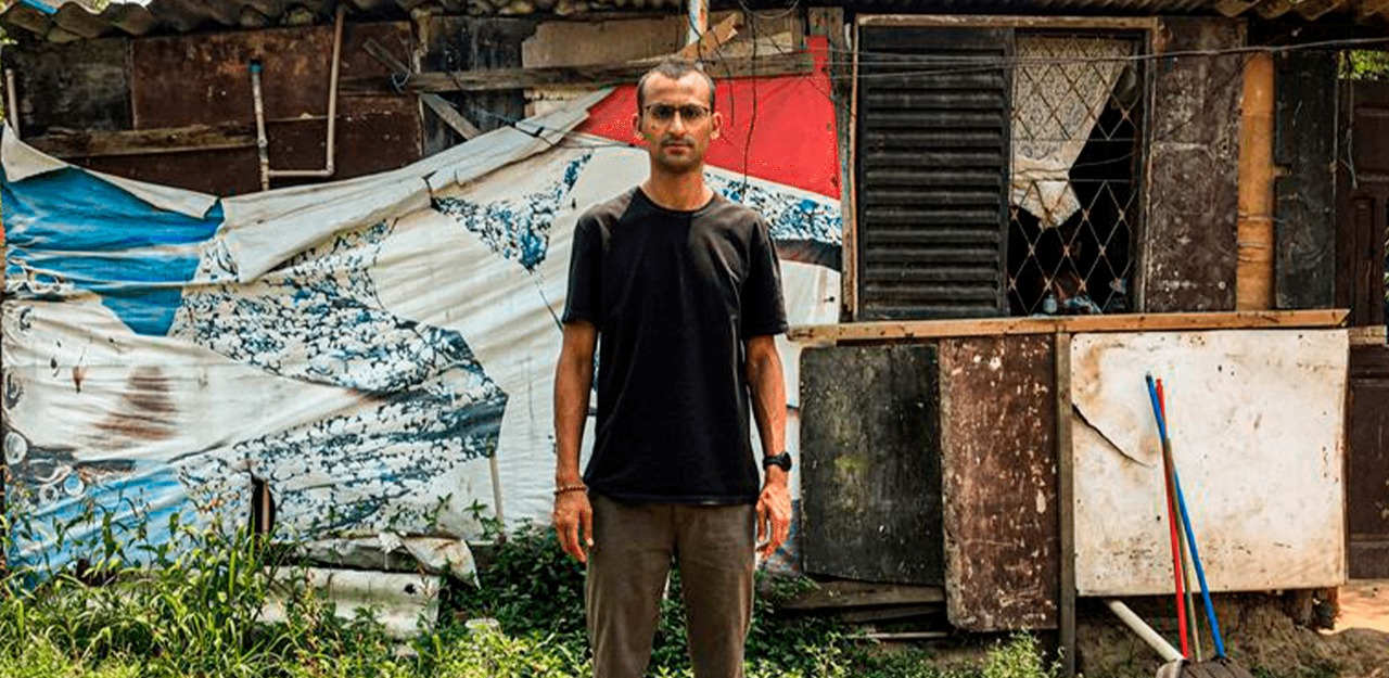 Edu Lira parado em frente a uma moradia na favela