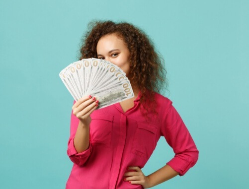 mulher com blusa rosa segurando notas de dinheiro