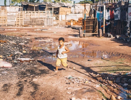 criança correndo perto de lama em vulnerabilidade social 