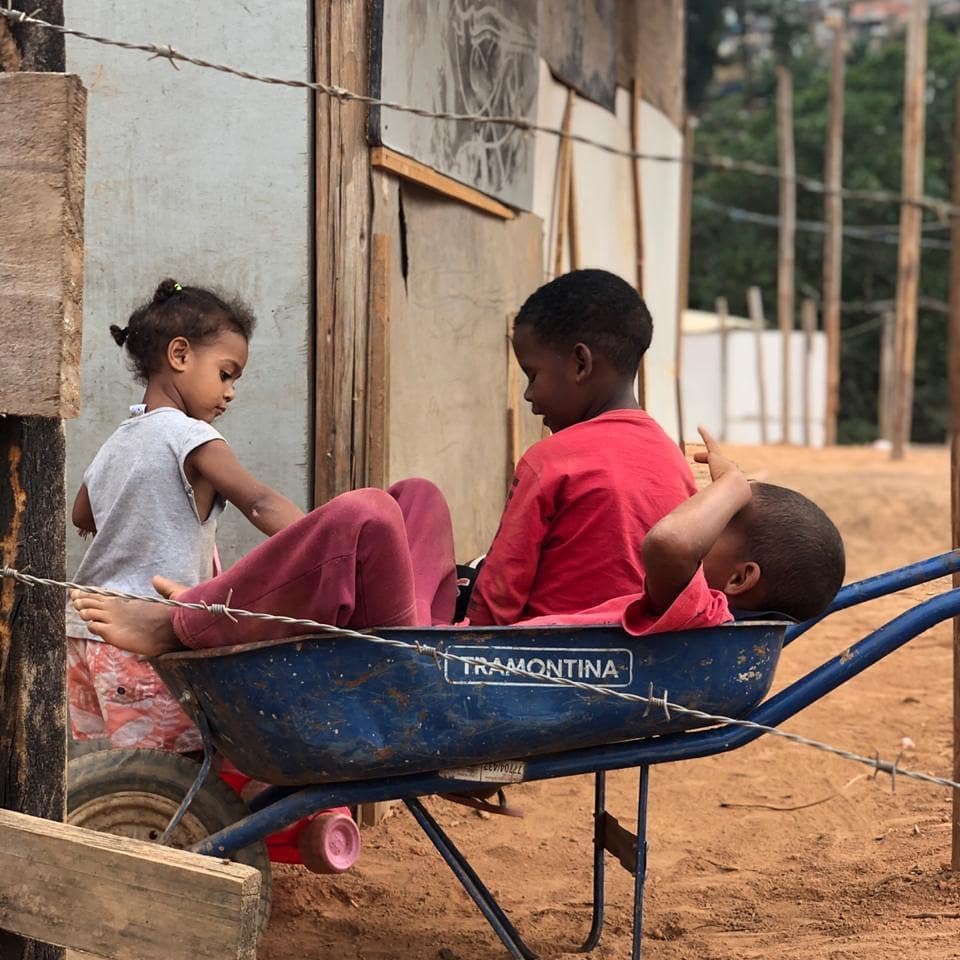 Crianças brincando com um carrinho de mão em favela