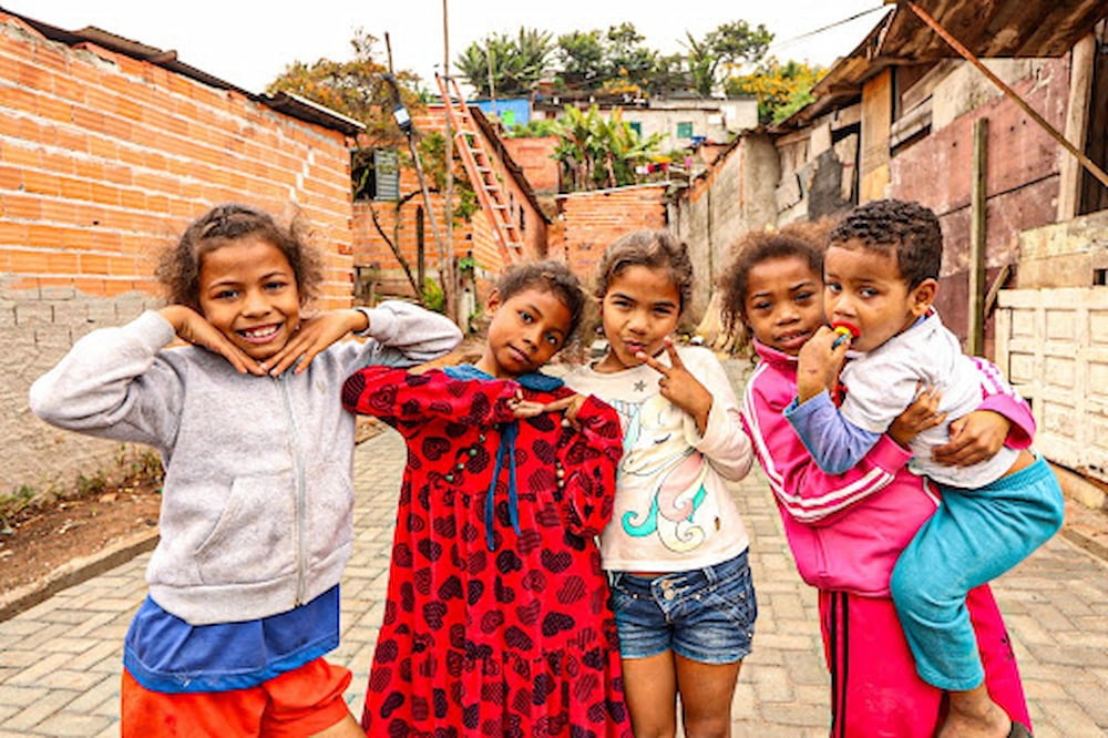 cinco crianças em uma região de favela, locais esquecidos pelos governantes, mas que recebem apoio diário através de projetos sociais